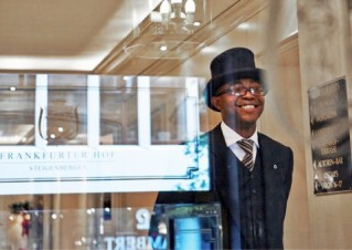 A Deutsche Hosüitality employee wearing a suit and top hat at the luxurious hotel Frankfurter Hof.